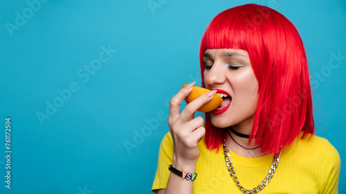 A young beautiful funny model bites off a slice of orange. Healthy vitamin food. Fresh fruit. Bright background. A place for your text.