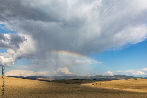 Heavy storm in the Tuscany countryside with dramatic light and colorful rainbow above the haystack 