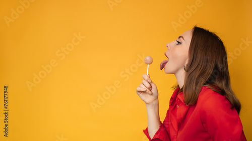 A surprised young funny girl is holding a lollipop in her hands and fooling around. A place for your text. photo