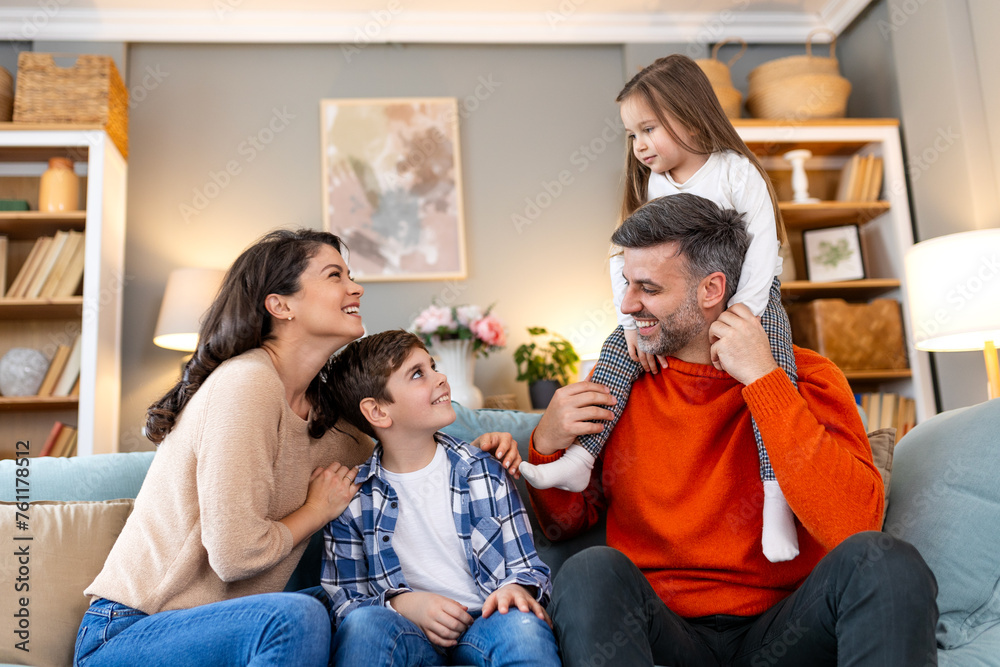 Cheerful family sitting on couch in living room have fun little daughter and son laughing together with parents enjoy free time playing at home. Weekend activity happy family lifestyle concept