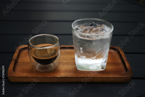 Hot coffee and glass of ice on wooden tray on wooden table