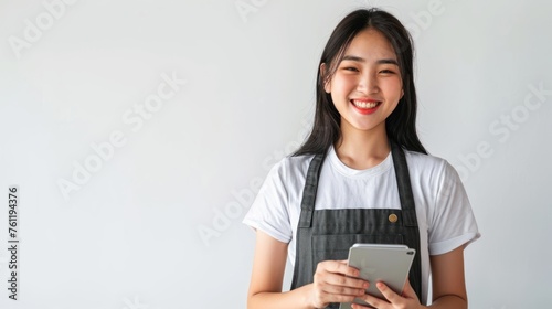 young smiling welcome asian female woman business owner wear apron hand holding tablet ready for your order on white color background, restaurant, pretty, uniform