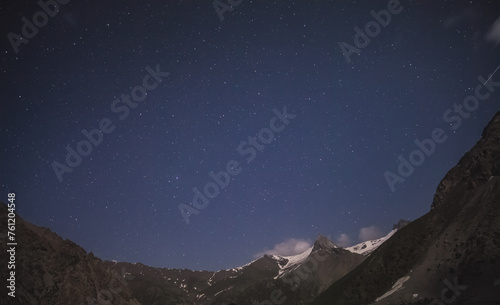  Night landscape of a mountain range with rocks, snow and glaciers in the Fan Mountains in Tajikistan, Tien Shan highlands on a starry moonlit night