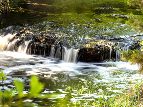 Everything Flows. Summer is here, but the water still gurgles between the green banks of the small stream.... photo