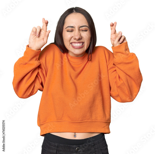 Modern young Caucasian woman portrait on studio background crossing fingers for having luck