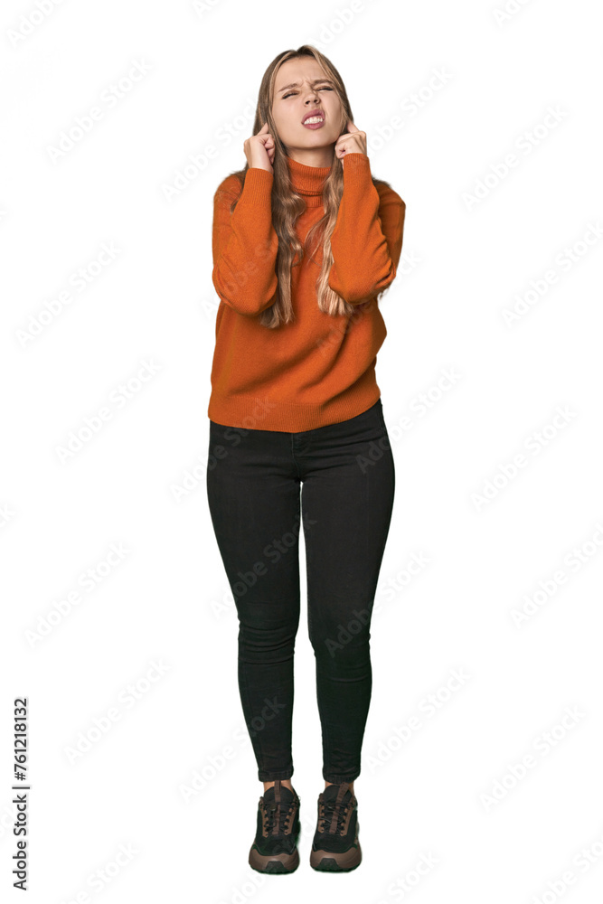 Fototapeta premium Studio portrait of a blonde Caucasian woman covering ears with fingers, stressed and desperate by a loudly ambient.