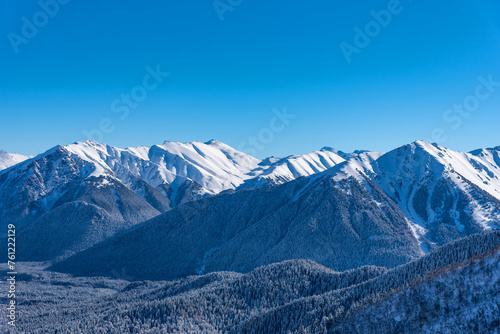 Beautiful landscape of the Arkhyz ski resort with mountains, snow, forest on sunny winter day. Caucasus Mountains, Russia.