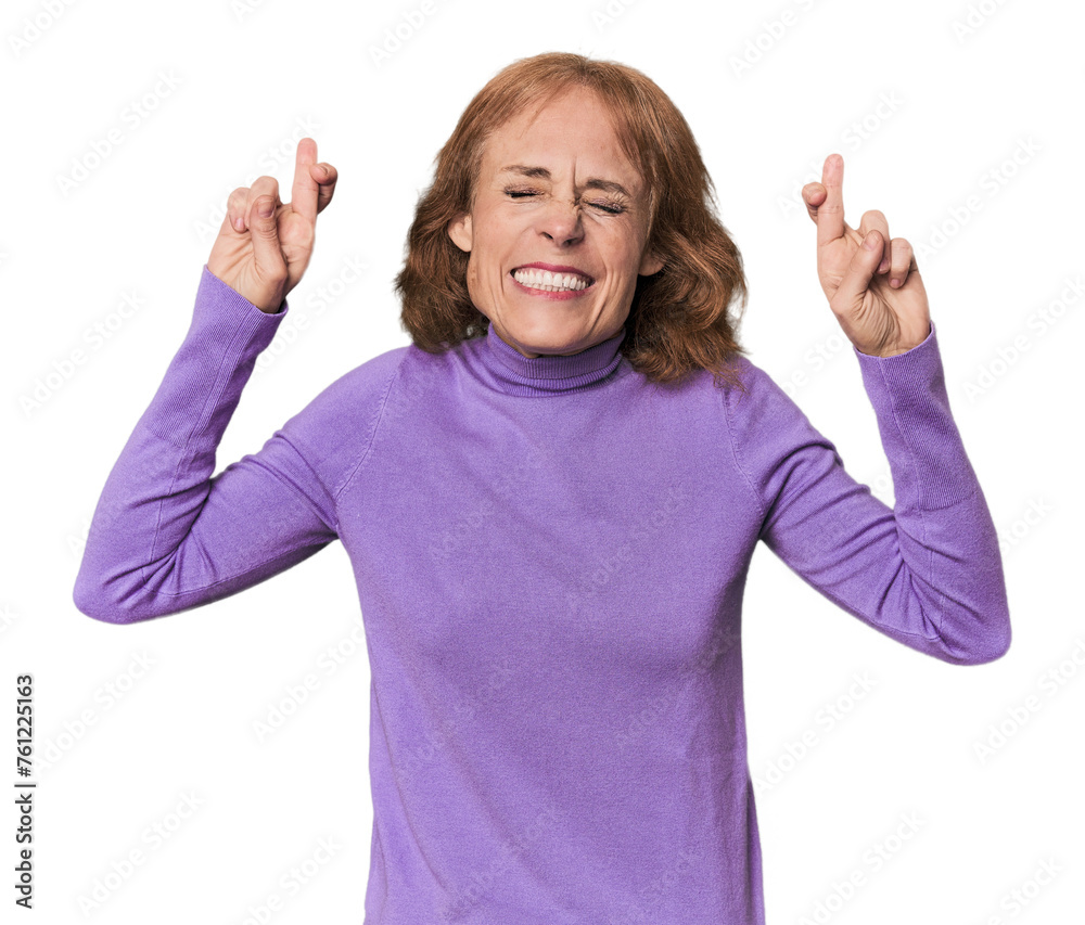 Redhead mid-aged Caucasian woman in studio crossing fingers for having luck Redhead mid-aged Caucasian woman in studio crossing fingers for having luck