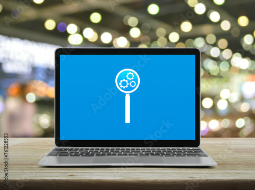 Seo icon on laptop computer monitor screen on wooden table over blur light and shadow of shopping mall, Search engine optimization concept