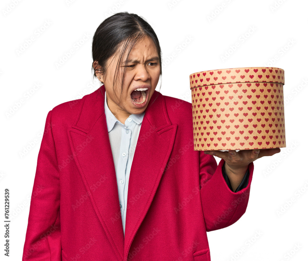 Young Chinese woman holding a heart-filled box screaming very angry and aggressive. Young Chinese woman holding a heart-filled box screaming very angry and aggressive.
