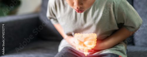 Fotografía Portrait of sick unhappy little child asian boy touching belly stomach with suff