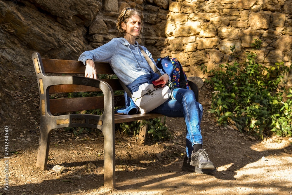 woman relaxing on a bench in barcelona with stone wall in the background woman relaxing on a bench in barcelona with stone wall in the background