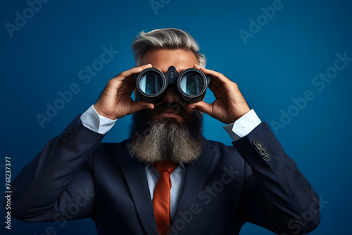 Portrait of  bearded man in a suit using binoculars to look into the distance photo