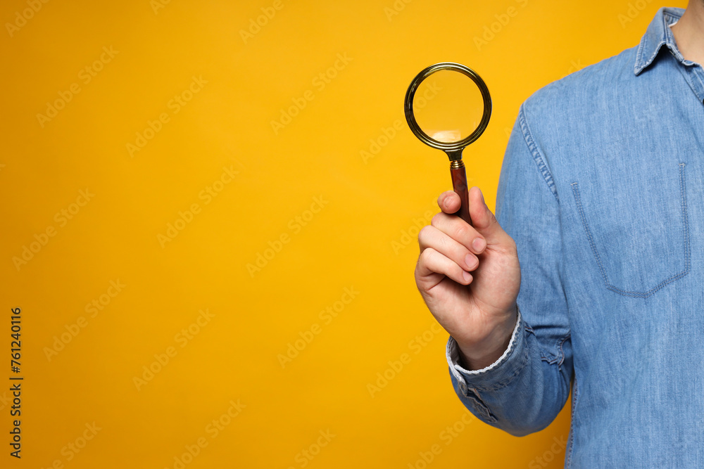 A magnifying glass in a man's hand on a yellow background A magnifying glass in a man's hand on a yellow background