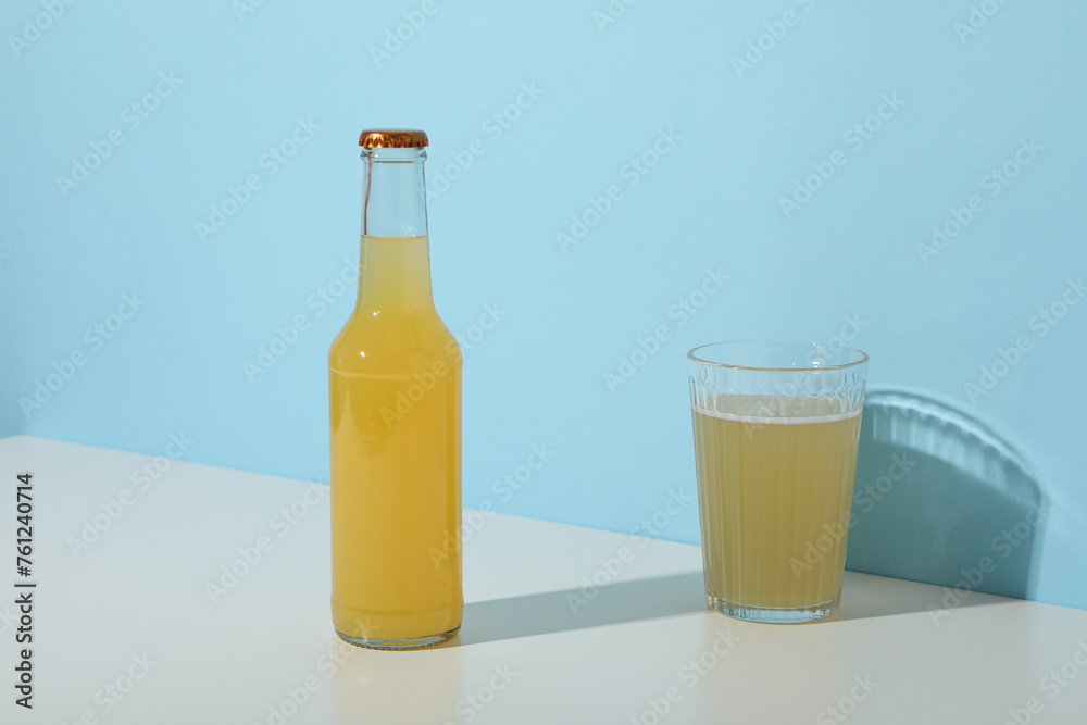 Glass and bottle with apple cider on blue background