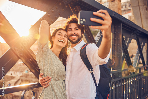 Cheerful couple taking selfie through smart phone at Dom Luis bridge, Porto, Portugal photo