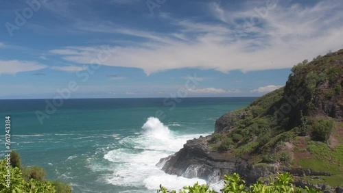 Large waves created by an offshore storm crash onto the cliffs on Kauai near Kilauea. Tropic birds roam the cliff side. photo