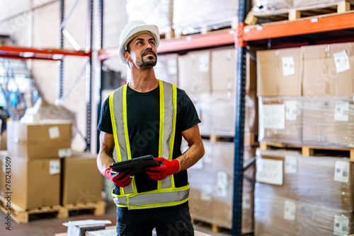 Smiling worker examining inventory with tablet PC at warehouse photo