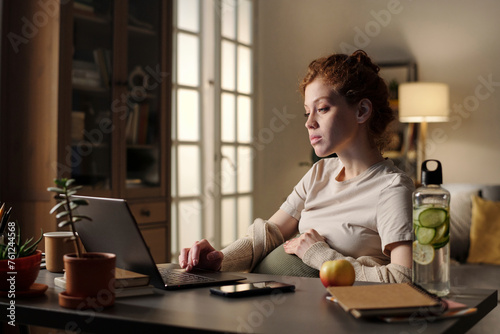 Young pregnant freelance working on laptop from home office photo