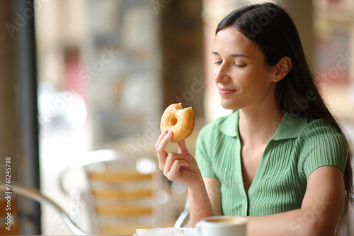 Woman eating doughnut in a terrace