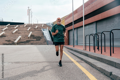 Determined senior man running on footpath photo