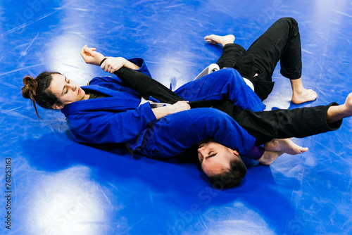 Athletes wearing kimono and practicing jiu-jitsu at dojo