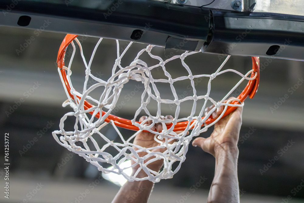 Symbolbild Dunking beim Basketball: Ein Spieler hat nach einem erfolgreichen Dunk noch die Hände am Korb