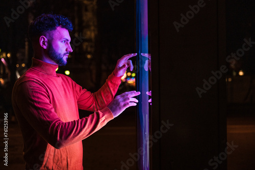 Man using touch screen kiosk at night photo