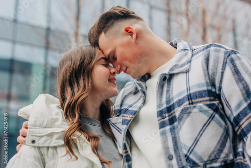 Romantic young couple rubbing noses in front of building photo