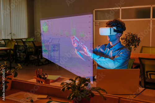 Businessman interacting with graphical interface using virtual reality simulator in office photo