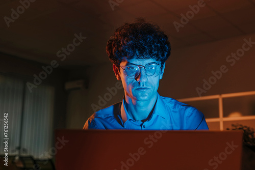 Businessman working on laptop in office at night photo