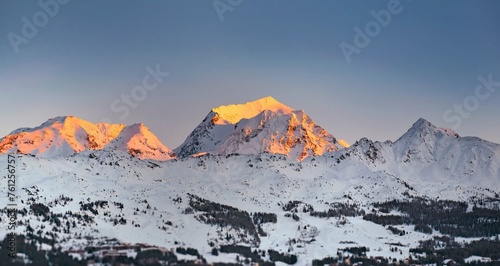 sunset on snowy mountain peak in alpine ski resort photo