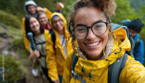 Close up of a young woman smiling at the camera while standing with a group on a mountain