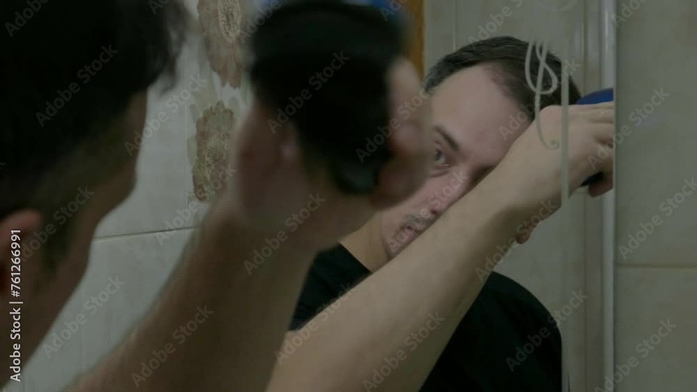 Brunet in bathroom in front of mirror brushing his hair. A man in the bathroom styling his hair Brunet in bathroom in front of mirror brushing his hair. A man in the bathroom styling his hair