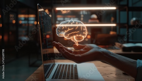 A hand holding a digital brain hologram above a laptop depicting an artificial intelligence concept in copy space. AI technology and machine learning concepts