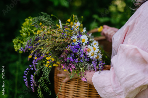 Woman holding wicker basket with meadow flowers. A colorful variety of summer wildflowers.