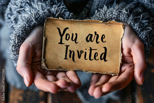 Hands holding an invitation card to an event written You are invited © Keitma
