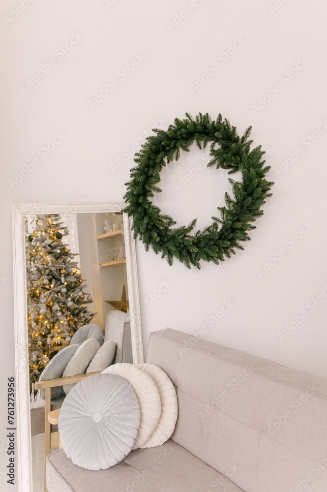 New Year's decor, a bright room with a Scandinavian interior, a sofa, a mirror and a Christmas wreath on the wall
