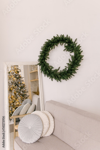 Obraz na płótnie New Year's decor, a bright room with a Scandinavian interior, a sofa, a mirror and a Christmas wreath on the wall w salonie
