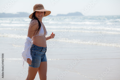 A beautiful girl with a wet hair and an Asian face type, a good slender figure posing on a sandy beach against the background of the ocean