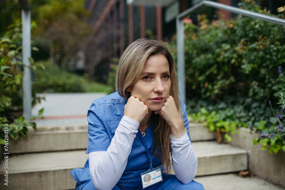Female doctor feeling overwhelmed at work, sitting on stairs. Healthcare workers with stressful job, feeling exhausted. Burnout syndrome for doctors and nurses. Female doctor feeling overwhelmed at work, sitting on stairs. Healthcare workers with stressful job, feeling exhausted. Burnout syndrome for doctors and nurses.