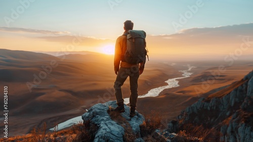 Hiker witnessing the golden sunrise over a serene mountain lake, embodying the spirit of adventure, outdoor exploration, hiking, and travel © TEERAPONG