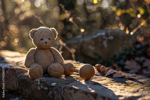 Resting on a sun-warmed stone ledge, a teddy bear and wooden rattle soak in the afternoon glow.