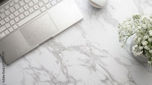 Notebook with keyboard with flowers in vase on white marble table. Top view of modern stylish workplace with laptop computer. Copy space. Flat lay.
