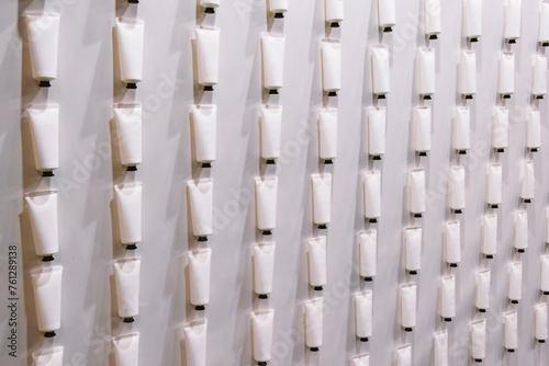 A background on which hangs a row of white cosmetic tubes with cream. The tubes are lined up to create a visually appealing display.