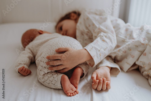 Quadro em tela Portrait of big sister cuddling newborn, little baby