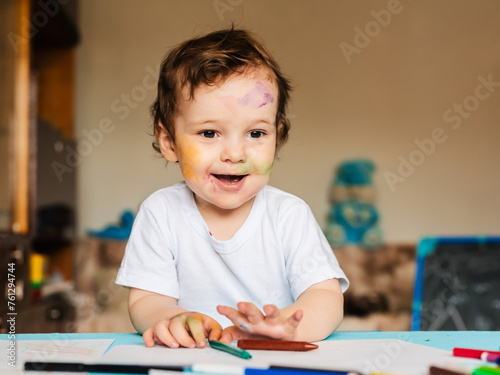 a small boy draws with colorful markers on a piece of paper