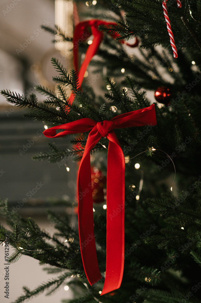 Beautiful New Year decor, the Christmas tree is decorated with red bows in the stylish interior of the living room