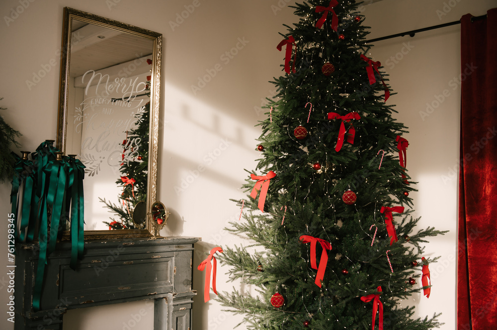 Beautiful New Year decor, the Christmas tree is decorated with red bows in the stylish interior of the living room