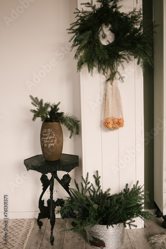Obraz na płótnie Beautiful New Year decor, a Christmas wreath made of spruce on the wall, a handmade woven string bag with tangerines w salonie